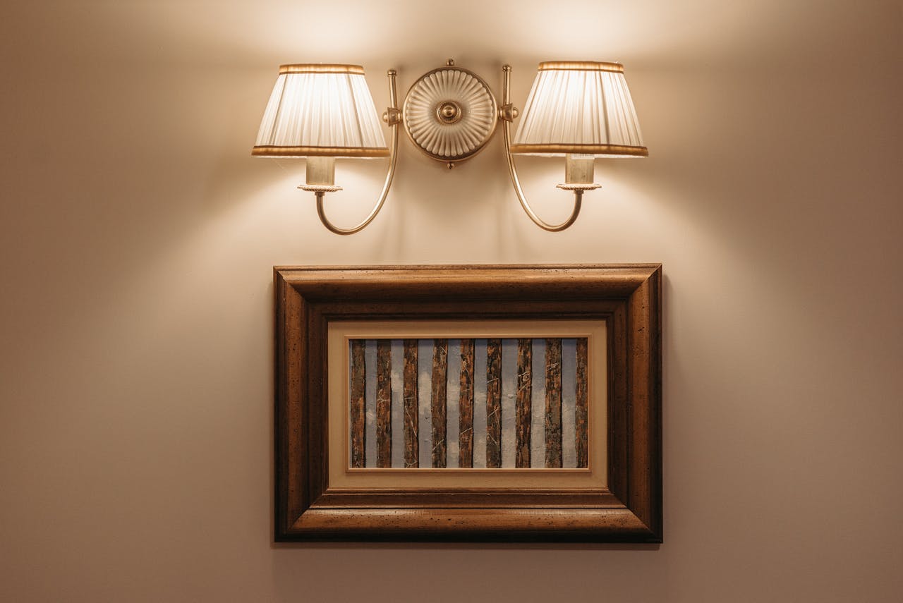 Softly lit wall light illuminating a framed artwork on a white wall.